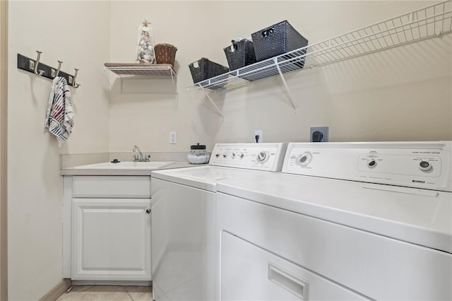 clothes washing area featuring washing machine and dryer, sink, light tile patterned flooring, and cabinets