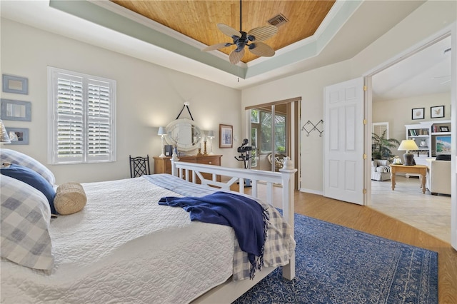 bedroom featuring ornamental molding, a tray ceiling, ceiling fan, wooden ceiling, and hardwood / wood-style floors