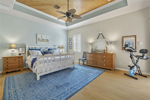 bedroom featuring ceiling fan, crown molding, hardwood / wood-style floors, a tray ceiling, and wood ceiling