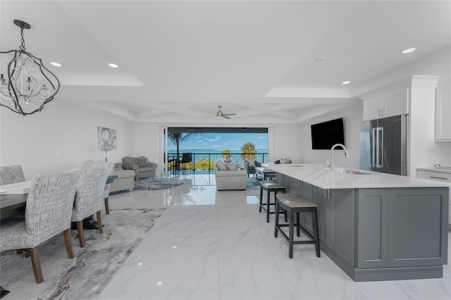 kitchen with ceiling fan, sink, pendant lighting, high end fridge, and white cabinets