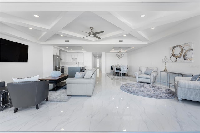 living room featuring beamed ceiling, coffered ceiling, ceiling fan with notable chandelier, and sink