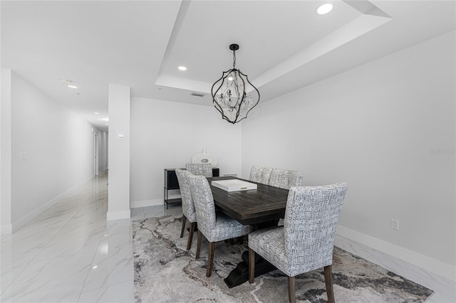 dining area featuring a tray ceiling and a chandelier