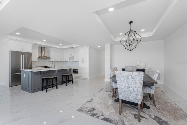 dining space with an inviting chandelier, sink, and a tray ceiling