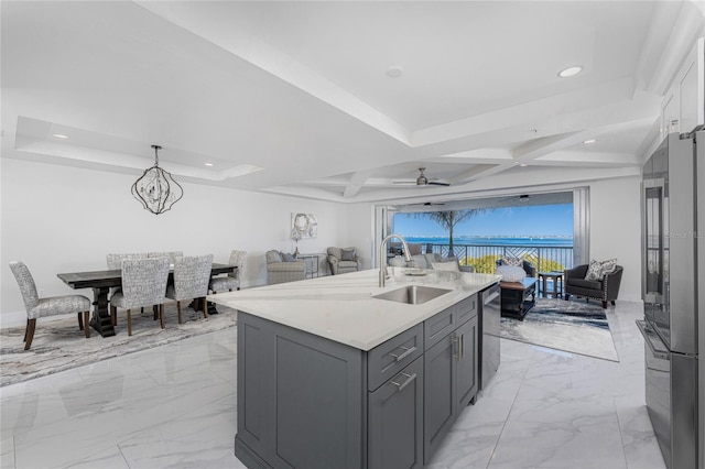 kitchen with sink, a kitchen island with sink, gray cabinetry, coffered ceiling, and ceiling fan with notable chandelier