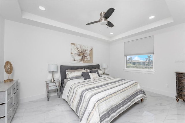 bedroom with ceiling fan and a tray ceiling