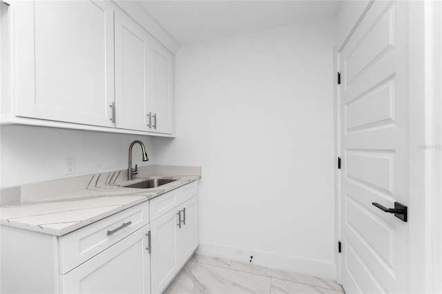 interior space with light stone counters, sink, and white cabinets