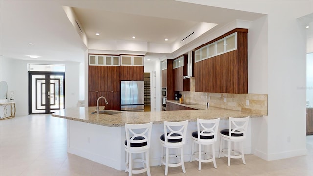 kitchen featuring kitchen peninsula, stainless steel refrigerator, sink, and a breakfast bar