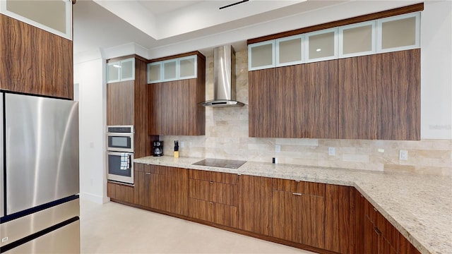 kitchen featuring wall chimney exhaust hood, light stone countertops, stainless steel appliances, and tasteful backsplash