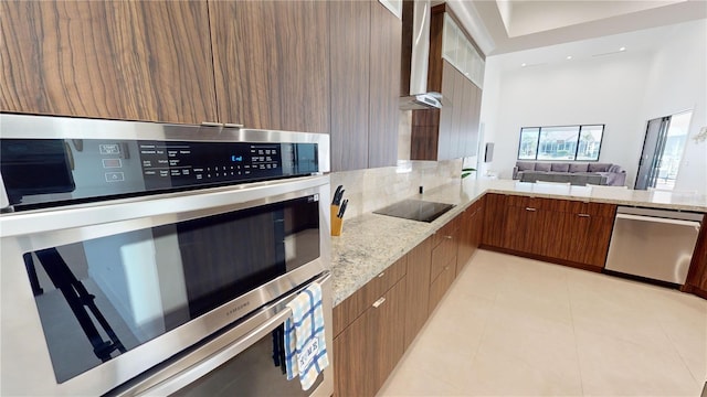 kitchen featuring wall chimney range hood, light stone counters, stainless steel dishwasher, black electric stovetop, and light tile patterned floors