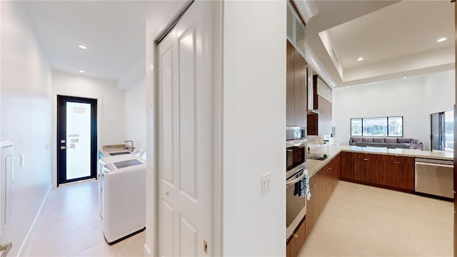 kitchen featuring separate washer and dryer, light tile patterned floors, stainless steel appliances, and kitchen peninsula