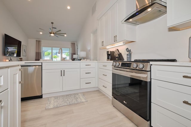 kitchen with appliances with stainless steel finishes, white cabinetry, lofted ceiling, and range hood