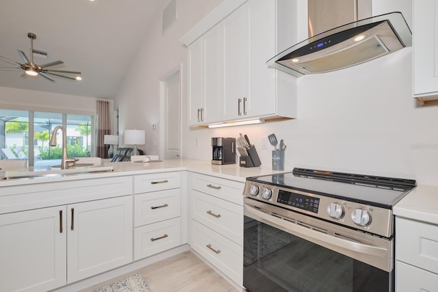 kitchen featuring stainless steel range, ventilation hood, vaulted ceiling, sink, and white cabinetry