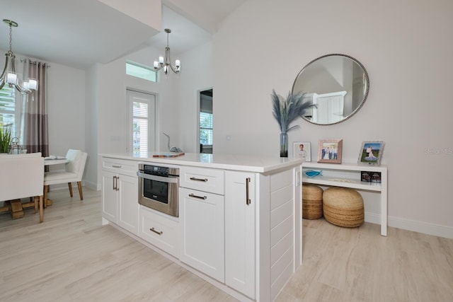 kitchen with white cabinetry, stainless steel oven, a center island, and hanging light fixtures