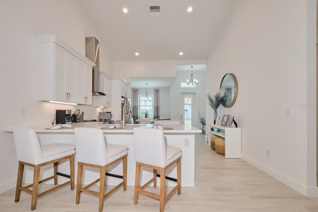 kitchen featuring a kitchen bar, kitchen peninsula, white cabinetry, and an inviting chandelier