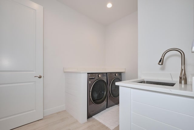 laundry area with separate washer and dryer, light hardwood / wood-style flooring, and sink