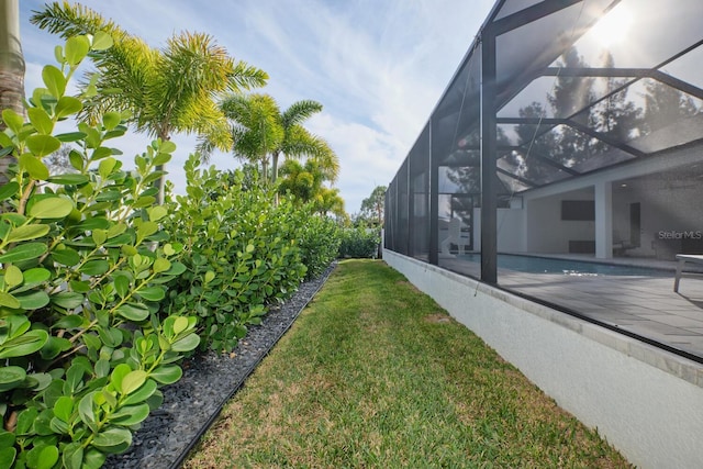 view of yard featuring glass enclosure and a patio