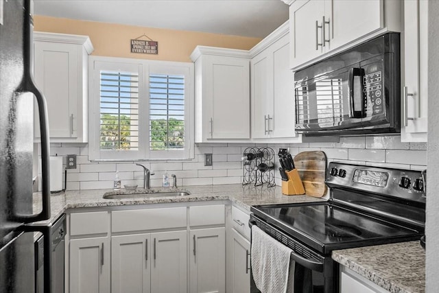 kitchen featuring sink, white cabinetry, black appliances, light stone countertops, and decorative backsplash