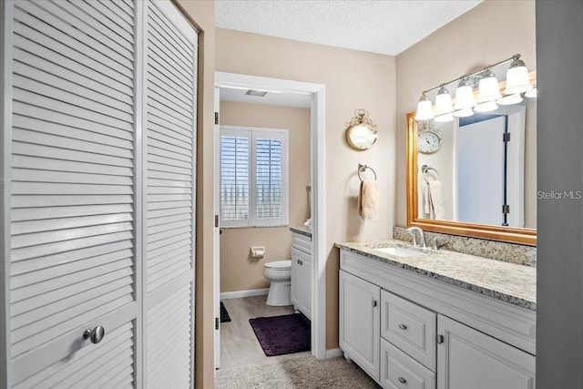 bathroom featuring vanity, toilet, and a textured ceiling