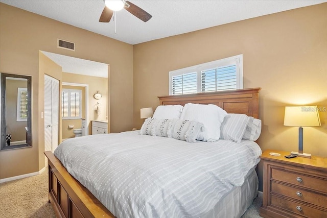 bedroom with multiple windows, connected bathroom, light colored carpet, and ceiling fan