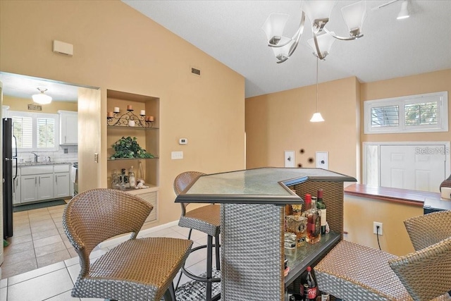 kitchen with tasteful backsplash, sink, vaulted ceiling, and light tile patterned flooring