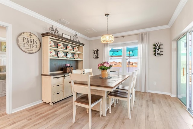 dining area with light hardwood / wood-style floors, ornamental molding, and an inviting chandelier