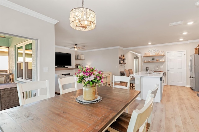 dining space featuring ceiling fan with notable chandelier, crown molding, and light hardwood / wood-style flooring