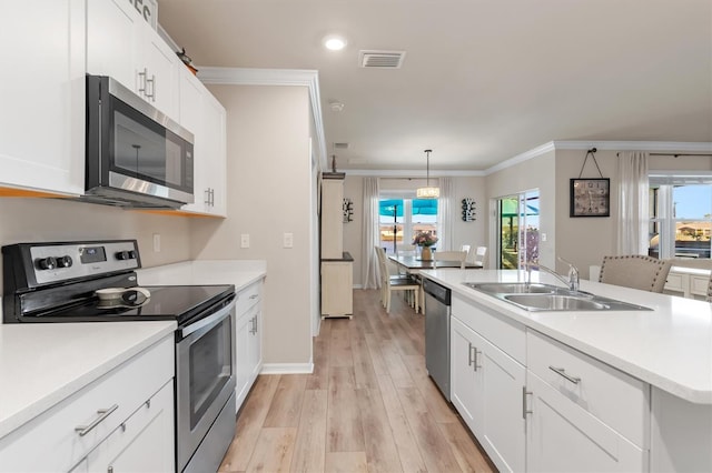 kitchen featuring sink, ornamental molding, decorative light fixtures, white cabinetry, and stainless steel appliances