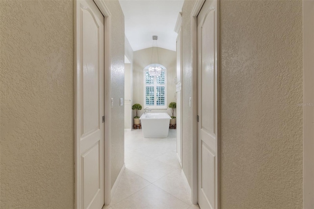 hall with lofted ceiling and light tile patterned floors