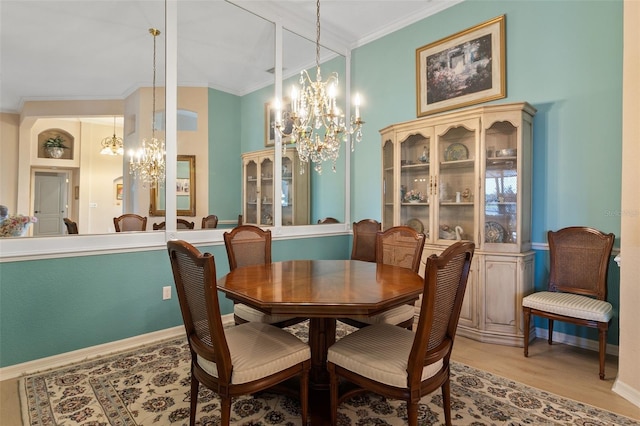 dining space with crown molding, a notable chandelier, and light wood-type flooring