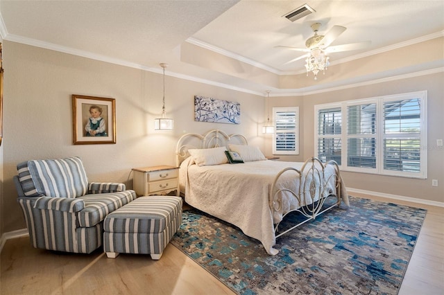 bedroom with ceiling fan, light wood-type flooring, crown molding, and a tray ceiling