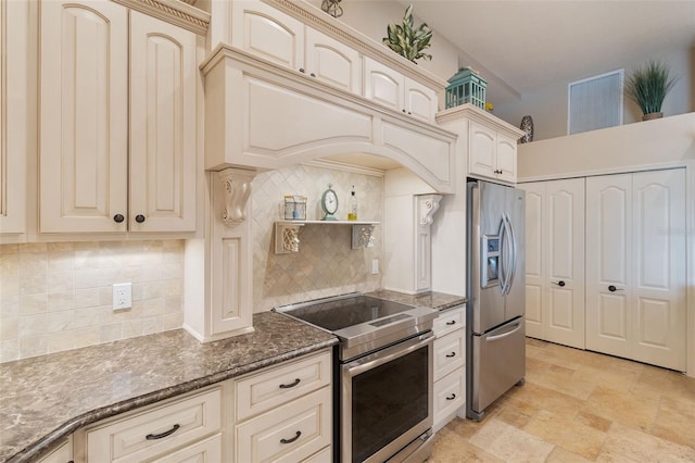 kitchen with cream cabinetry, appliances with stainless steel finishes, backsplash, and dark stone counters