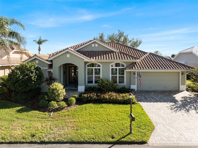 mediterranean / spanish-style house featuring a garage and a front lawn