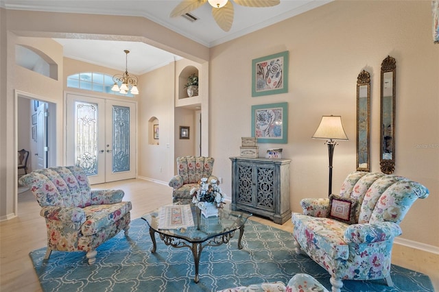 living area with french doors, crown molding, ceiling fan with notable chandelier, and light hardwood / wood-style flooring