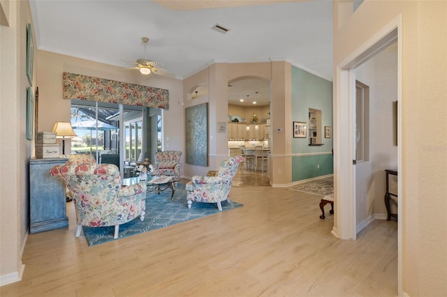 living room with wood-type flooring, ceiling fan, and crown molding