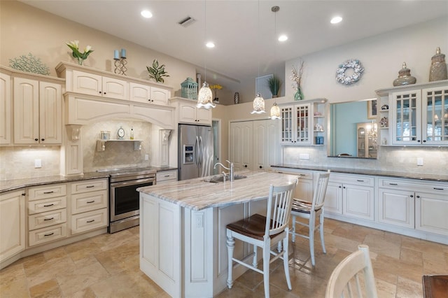 kitchen featuring pendant lighting, a kitchen breakfast bar, stainless steel appliances, light stone countertops, and a center island with sink