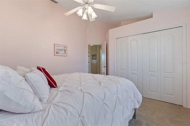 bedroom featuring ceiling fan, a closet, light carpet, and lofted ceiling