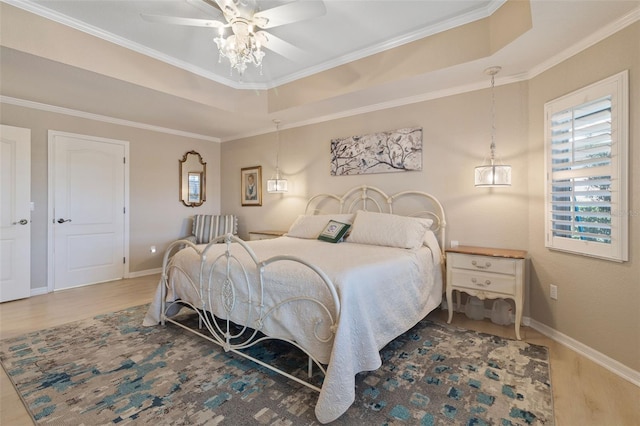 bedroom featuring a raised ceiling, crown molding, hardwood / wood-style floors, and ceiling fan