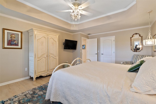 bedroom featuring a tray ceiling, ceiling fan, light hardwood / wood-style floors, and ornamental molding