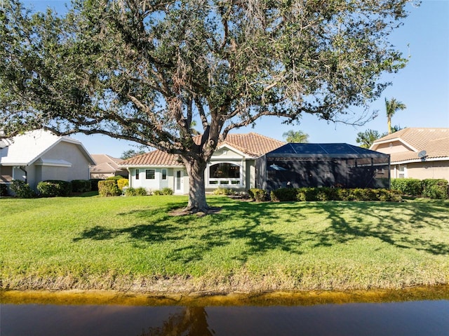 rear view of property featuring a yard, a water view, and glass enclosure