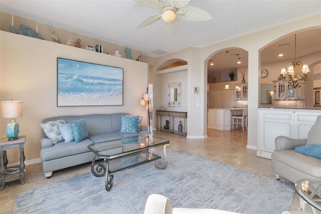 tiled living room featuring ceiling fan with notable chandelier