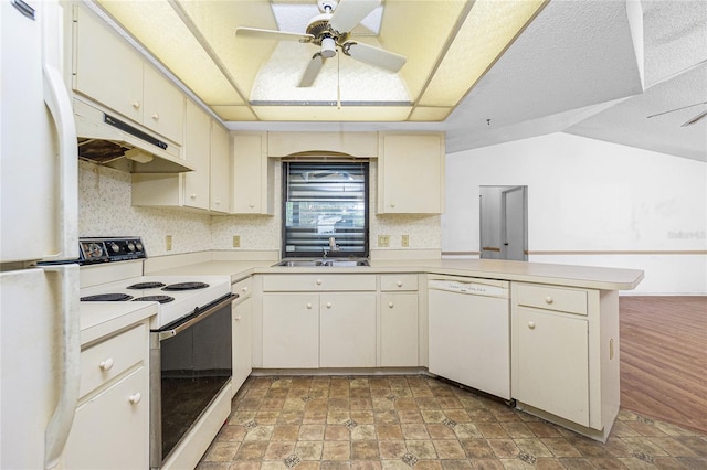 kitchen featuring sink, ceiling fan, kitchen peninsula, a raised ceiling, and white appliances