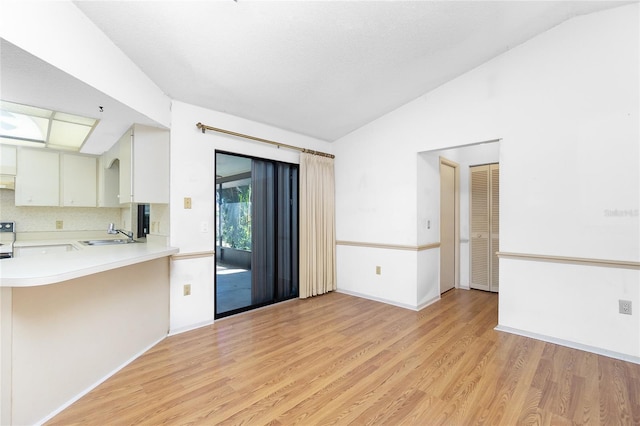 kitchen featuring lofted ceiling, white cabinetry, kitchen peninsula, and light wood-type flooring