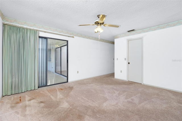 empty room with ceiling fan, light carpet, and a textured ceiling