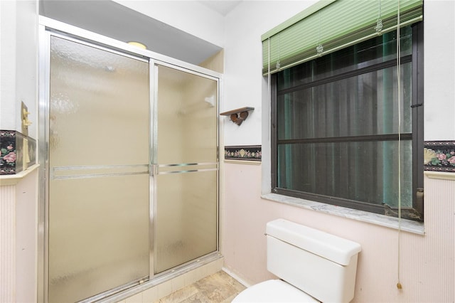 bathroom featuring toilet and a shower with shower door