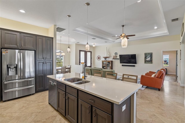 kitchen featuring appliances with stainless steel finishes, ceiling fan with notable chandelier, sink, a center island with sink, and hanging light fixtures