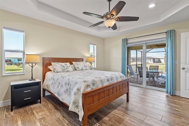 bedroom featuring a raised ceiling, ceiling fan, hardwood / wood-style floors, and access to outside