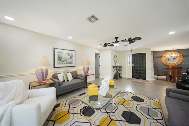 tiled living room with ceiling fan with notable chandelier