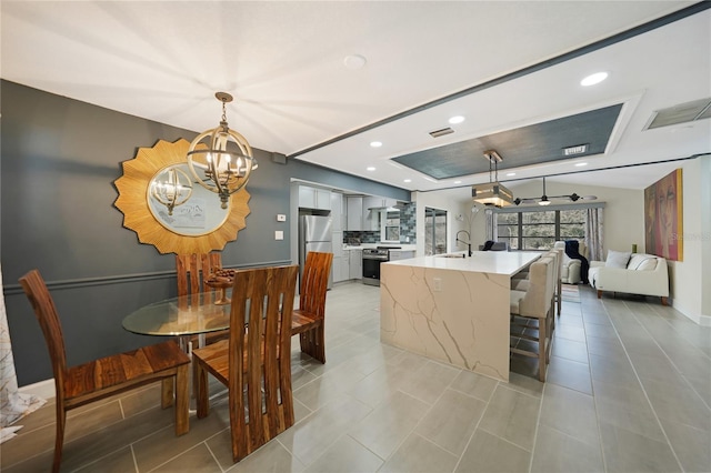 dining room with sink and ceiling fan with notable chandelier