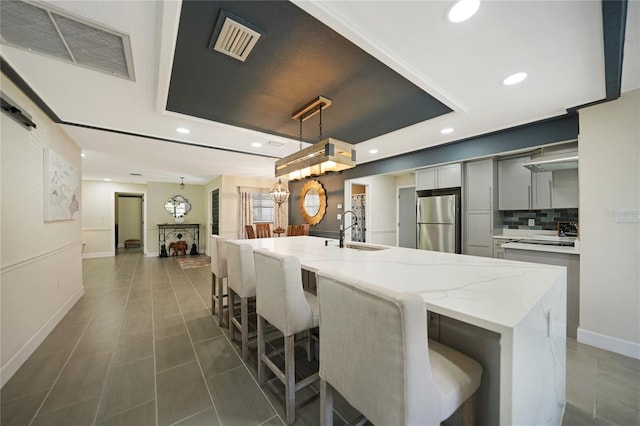 kitchen featuring pendant lighting, a large island, stainless steel fridge, and sink