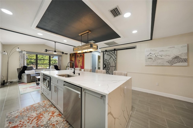 kitchen featuring sink, hanging light fixtures, stainless steel appliances, a barn door, and an island with sink